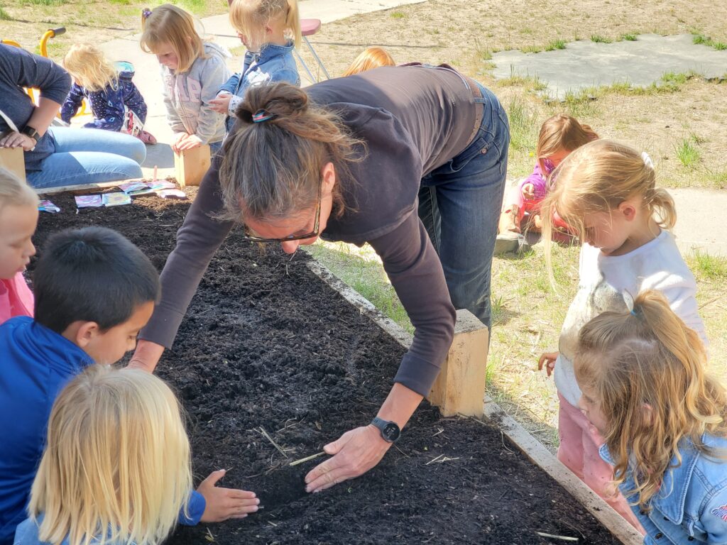 Modoc Harvest education coordinator, Jenny Kapp, engages in spring planting with Budding Tree students.